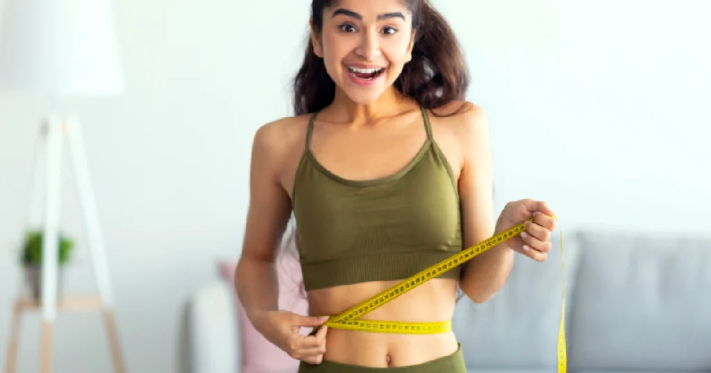 Happy young woman measuring slimmer waistline after weight loss results from Semaglutide Shots in Simi Valley, CA.