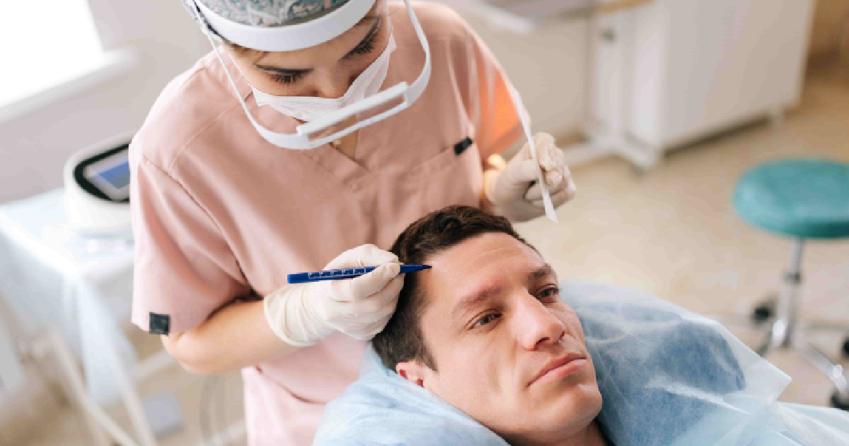 High-angle shot of a man lying down during an Aquafirm Hair Restoration in Simi Valley, CA, while a medical professional marks his forehead, wearing protective gear.
